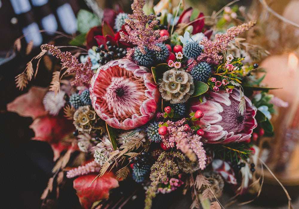 Autumn colors abound in this purple, blue and brown floral arrangement