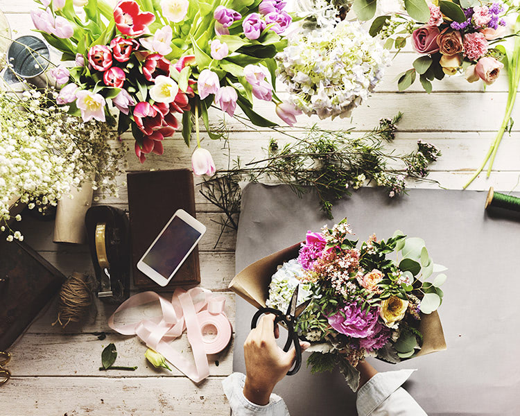 Various flowers, plants and accents atop a wooden workbench